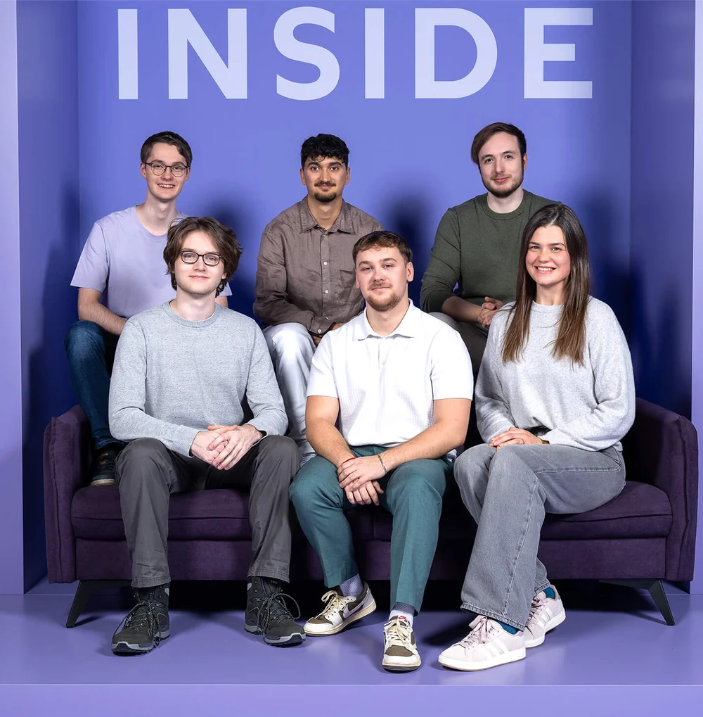 Sechs Personen sitzen und stehen vor einem lila Hintergrund mit dem Wort "INSIDE" oben. Sie sind entspannt gekleidet und blicken lächelnd in die Kamera.